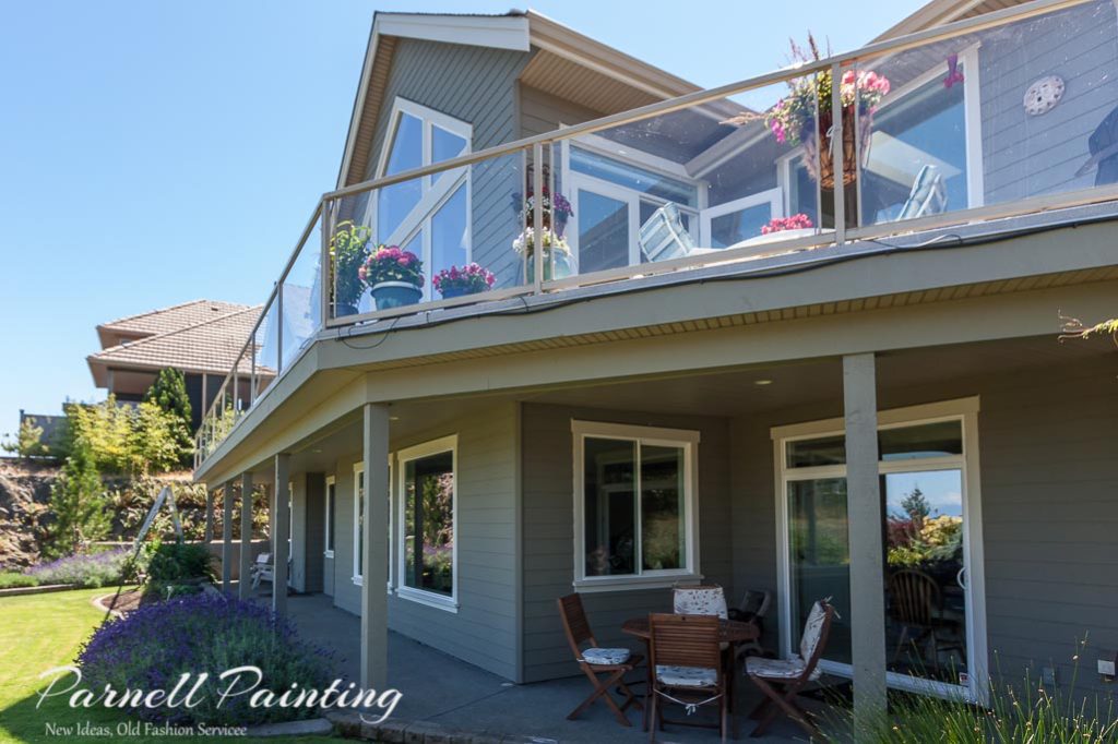 large two storey hardie board sided house painted a green-gray colour with a light creamy gray trim
