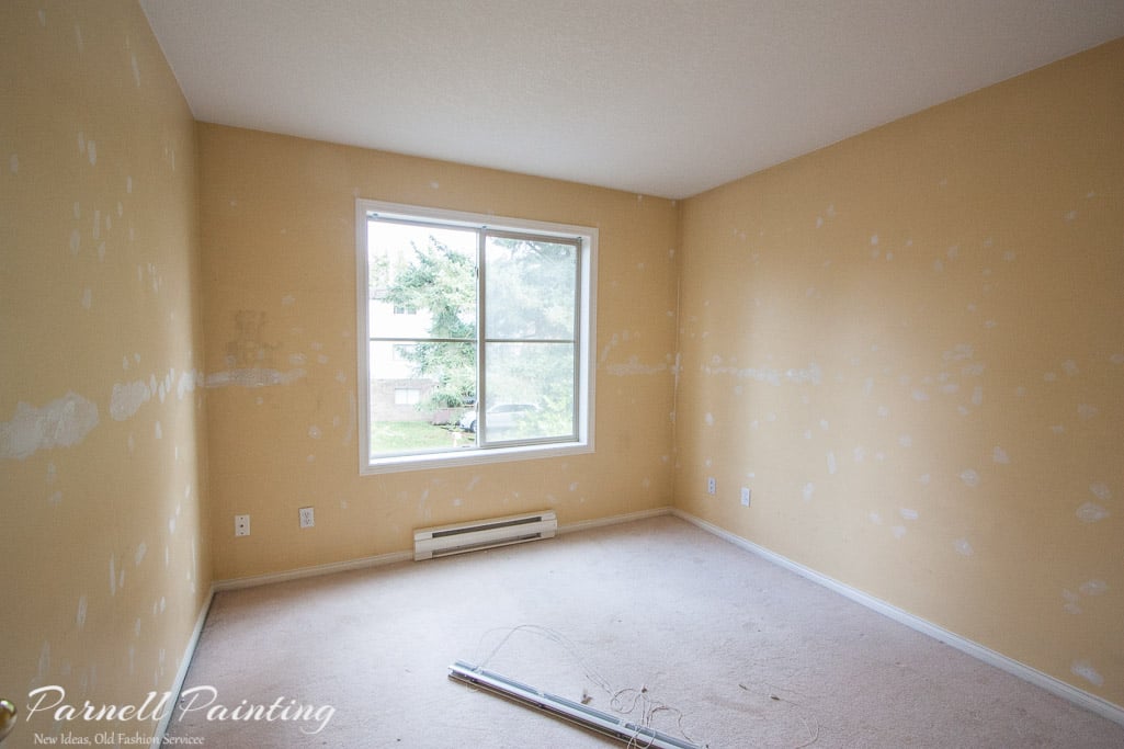 a yellow bedroom with an extensive amount of wall patching and repair