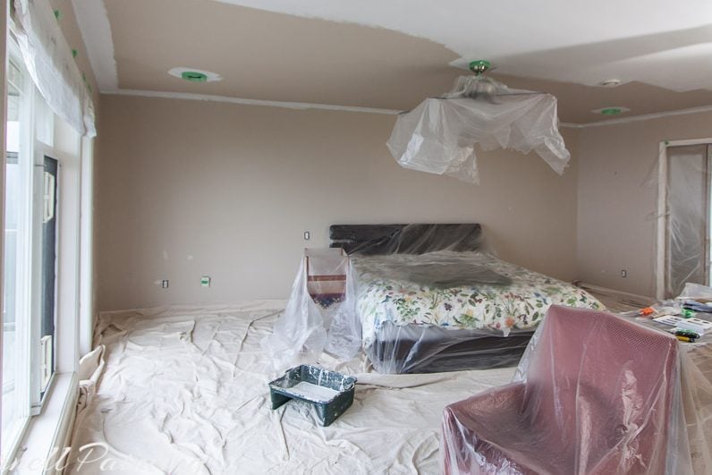 Beige primary bedroom ceiling in the process of being painted white showing how much brighter it will make the room.